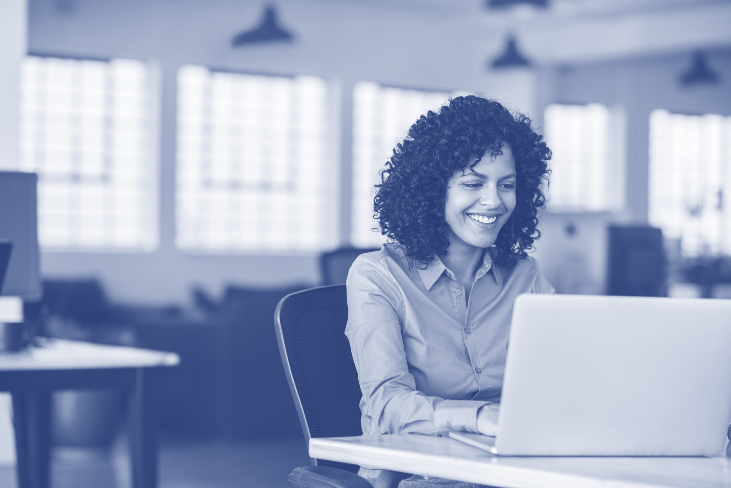 Smiling young businesswoman working on a laptop at her desk