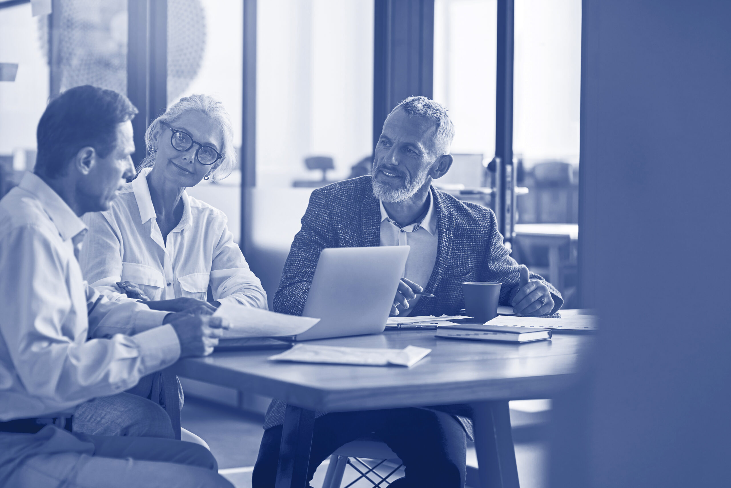 Three mature colleagues sitting in the modern office and discussing business strategy, business people working together
