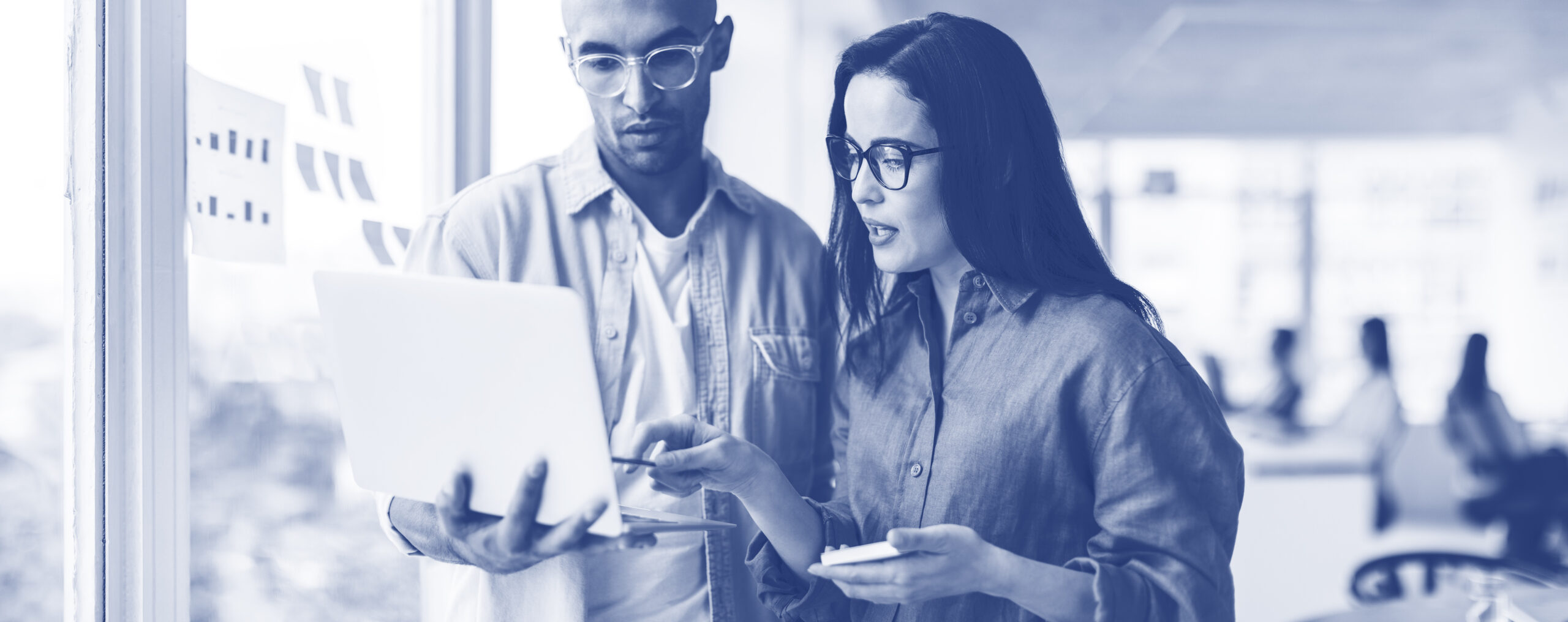 Business people standing in an office and using a laptop