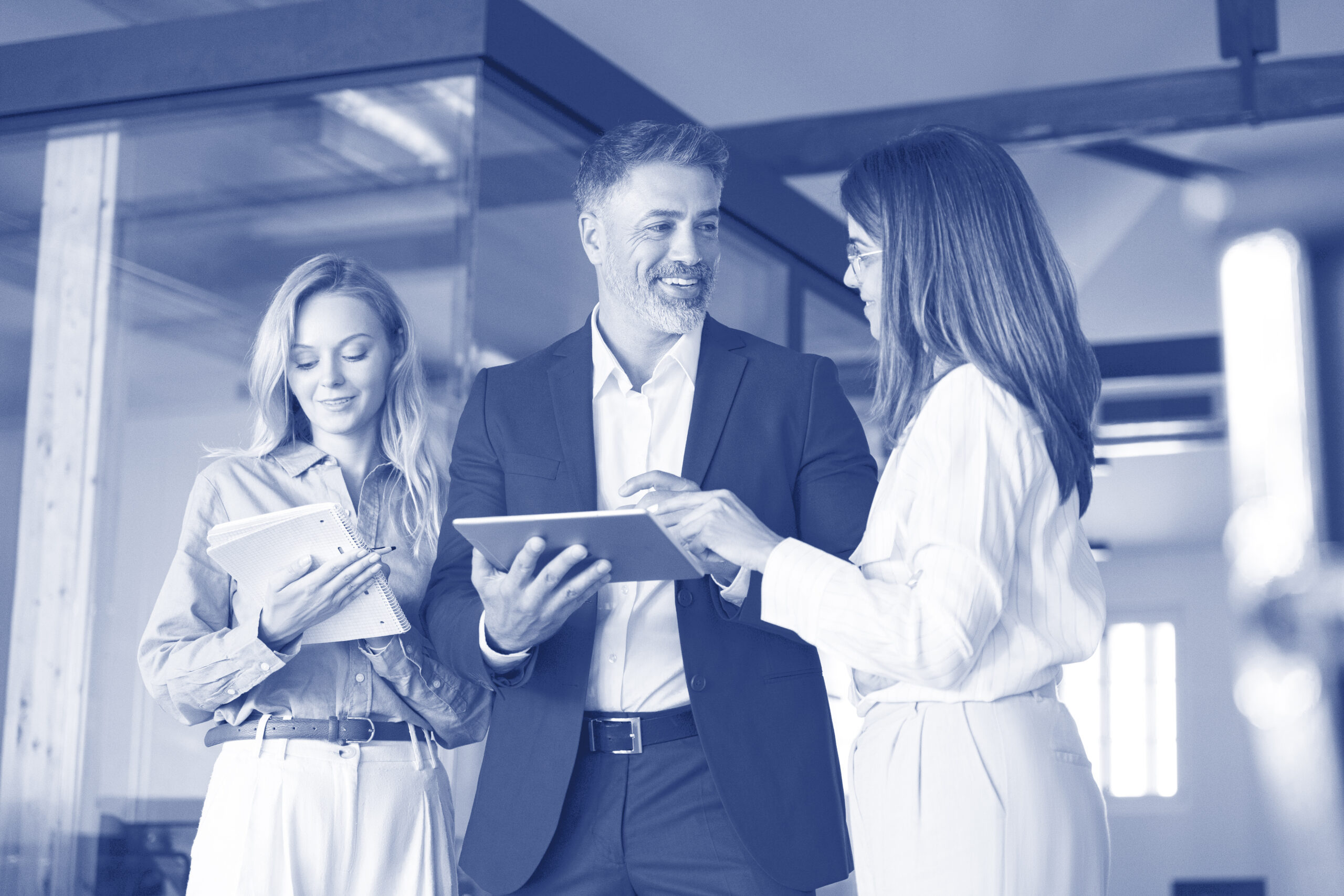 Group of diverse partners mature Latin business man and European business women discussing financial data market on tablet in office. Team of colleagues professionals business people working together.