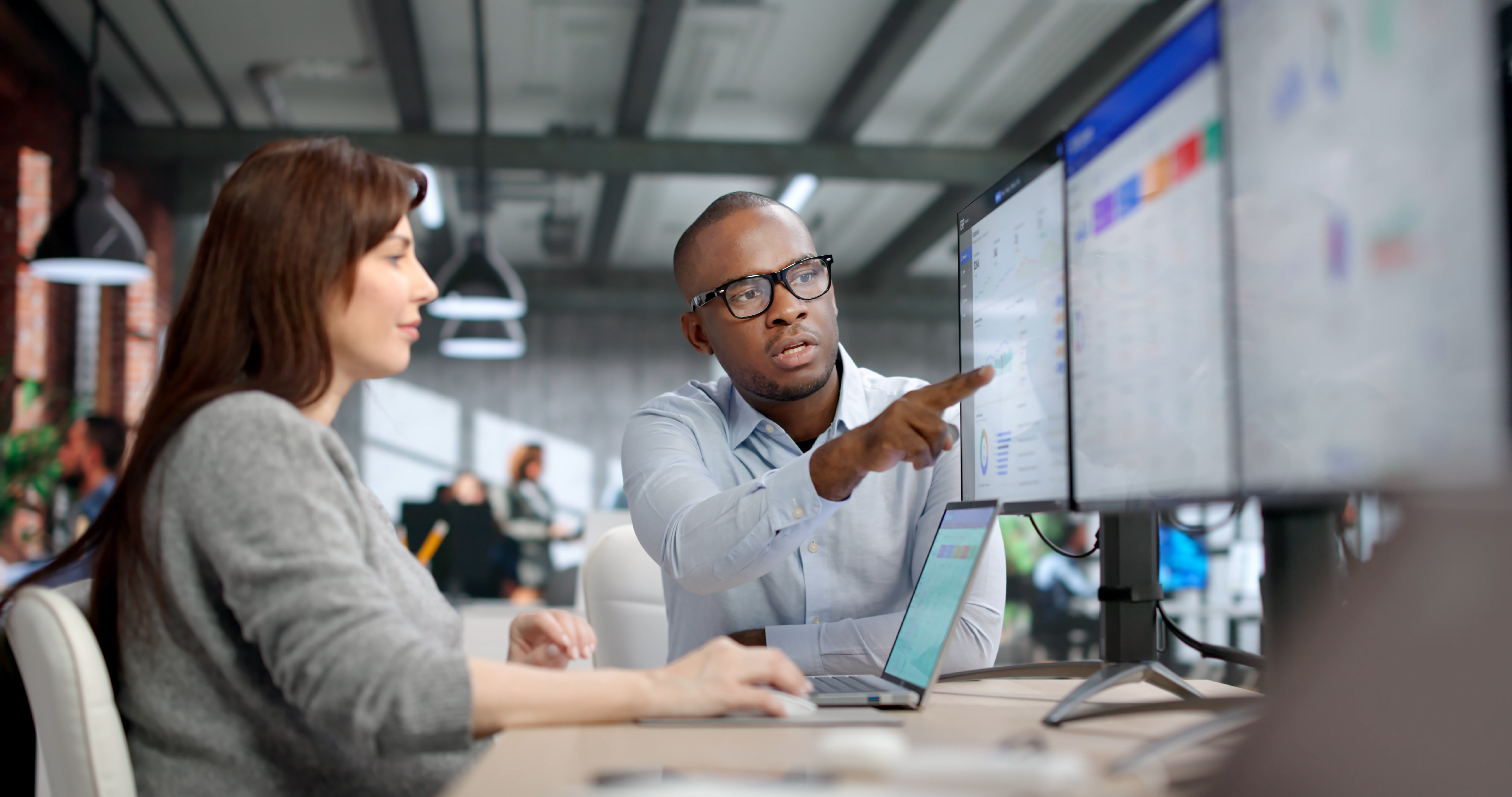 Two Young Professionals Collaborate Using ERP And CRM Software