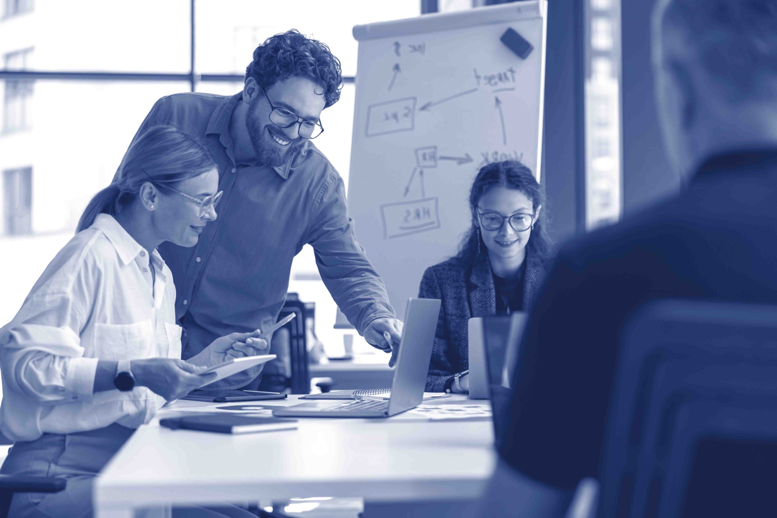 Group of young business people discussing something and smiling while sitting at the office table